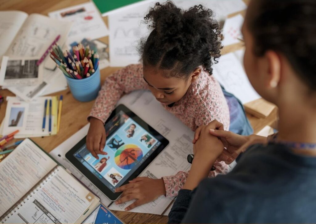 Bambina apprende con tablet e materiali scolastici.