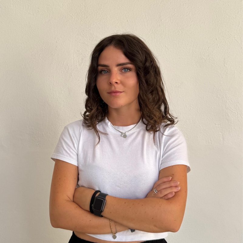 Donna in maglietta bianca con braccia incrociate.